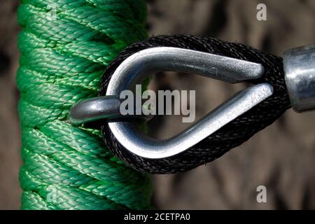 Texture of a green rope. A metal hook is attached to it. Here is another black rope. Stock Photo