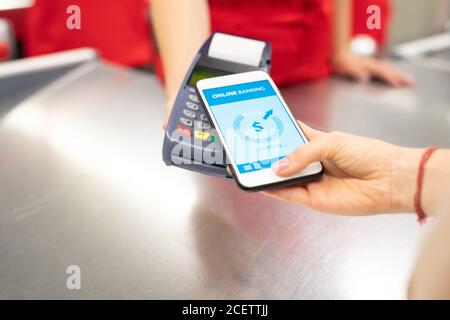 High angle close-up shot of unrecognizable young woman using online banking technology on smartphone to pay for goods in store Stock Photo