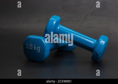 A pair of blue dumbbells on a black background Stock Photo