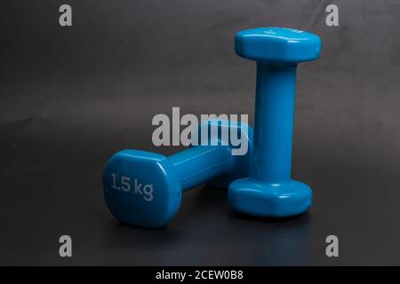 A pair of blue dumbbells on a black background Stock Photo