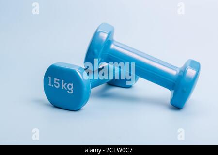 A pair of blue dumbbells on a blue background Stock Photo