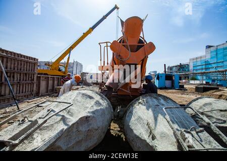 Old phosphate fertilizer plant in modernization. Construction of new industrial buildings. Mobile crane, workers, orange mixer truck, cement buckets, Stock Photo