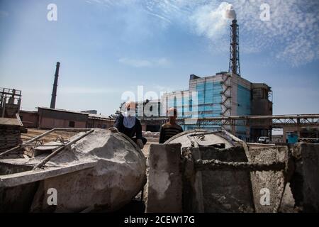 Old phosphate fertilizer plant in modernization. Construction of new industrial buildings. Workers with cement buckets.  Smoking chimney and industria Stock Photo