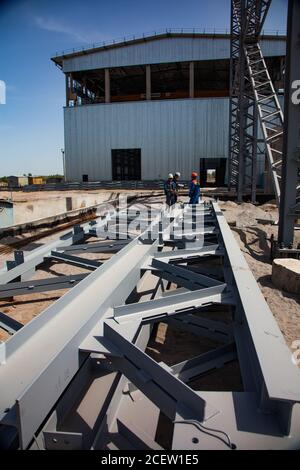 Old phosphate fertilizer plant in modernization. Developing of new factory building. Steel structure elements, on industrial building and blue sky bac Stock Photo