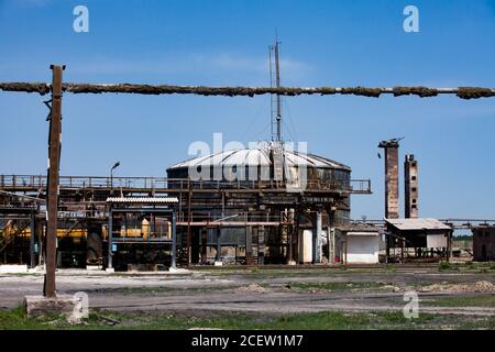 Old rusted oil tanks and pipe on soviet factory or plant. Blue sky background. Stock Photo