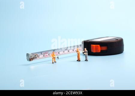 Meter stick and worker on blue background Stock Photo