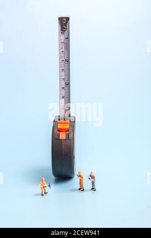 Meter stick and worker on blue background Stock Photo