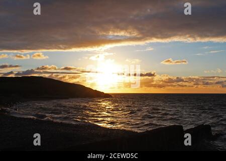 Beautiful golden, cloudy sunset over a sea bay and headland at Trefor, North Wales Stock Photo