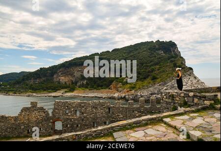 View of the Gulf of Poets from the city walls of the old fishing village with a tourist and the Palmaria Island, Porto Venere, La Spezia, Italy Stock Photo