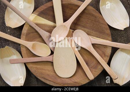 Top view on kitchenware made of recyclable materials: Spoons on wooden plate and bamboo paper bowls Stock Photo