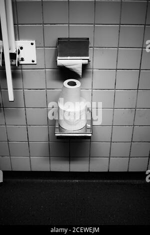 Creative image in black and white in grungy textured style of  toilet paper in a dirty bathroom. Stock Photo