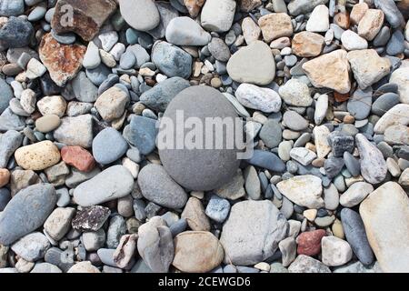 Pebbles, stones, rocks, beach background with a perfect round stone in Criccieth, North Wales Stock Photo