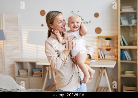 Horizontal medium shot of happy young woman holding her cute baby son in arms, copy space Stock Photo