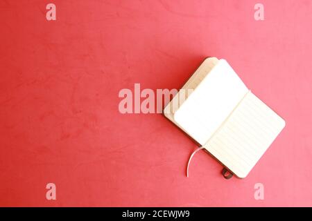 Top view of an open notebook on a red surface Stock Photo