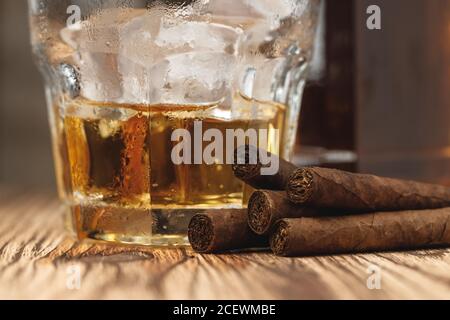 Glass of whiskey and rolled cigars on wooden table Stock Photo