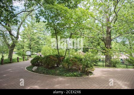 Naperville, Illinois, United States-April 24,2014: People walking along the brick riverwalk path with plantings and greenery in Naperville Stock Photo