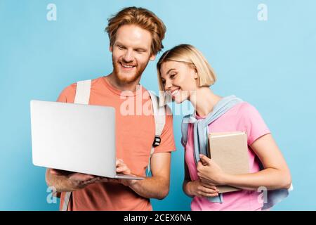 redhead and blonde students looking at laptop on blue Stock Photo
