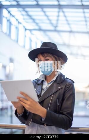 Trendy woman in mask using tablet indoors during pandemic Stock Photo