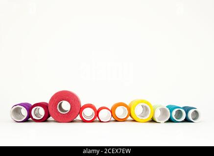 Flat lay with colorful cotton thread spools, embroidery yarn, rainbow bobbins, mock up, top view. Layout mockup on blank white background for Stock Photo