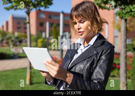 Young brunette caucasian 20s urban woman in park using digital tablet Stock Photo