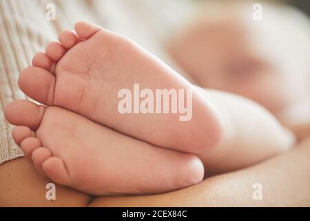 Horizontal close-up shot of lovely Caucasian baby boy's feet, his mother is cuddling him Stock Photo