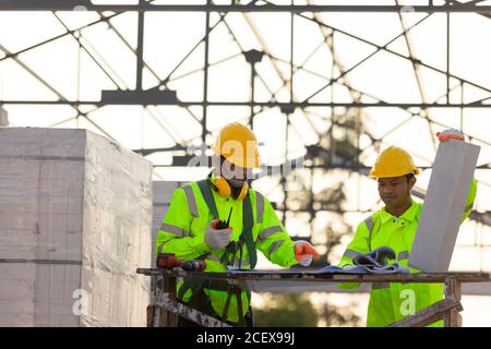 Asian engineers and consultant workers calculate the amount of bricks used in construction, Concept of construction team work. Stock Photo