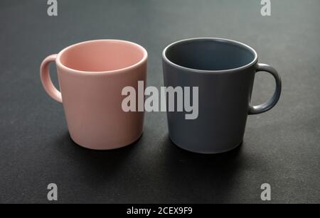 Coffee mugs on black background. Hot beverage cup mockup. Pink and gray color blank cups with handle advertise, branding template Stock Photo
