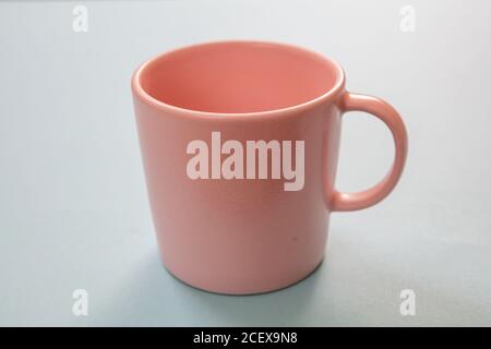 Coffee mug on pastel blue background. Hot beverage cup mockup. Pink color blank cup with handle advertise, branding template Stock Photo
