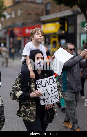 A young boy rides piggyback at the Million People March, London, 30 August 2020 Stock Photo