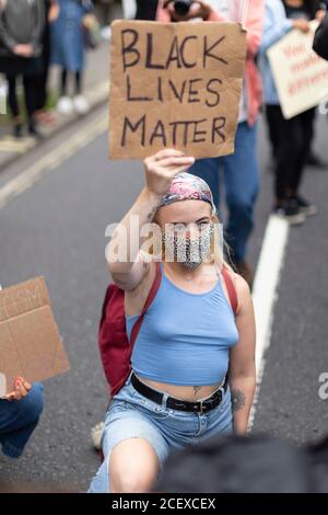 A girl taking the knee and holding up a protest sign at the Million People March, London, 30 August 2020 Stock Photo