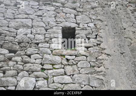 Stone Wall Texture. Large rough natural stone wall and hole for window in the middle - seamless texture for design. Stock Photo