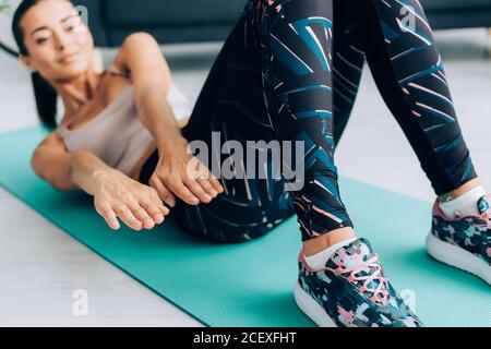 Selective focus of young woman doing abs while working out on fitness mat at home Stock Photo