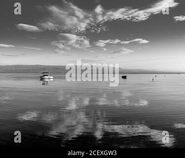 Symmetrical reflection and boats on the lake Geneva, France. Black and white image Stock Photo