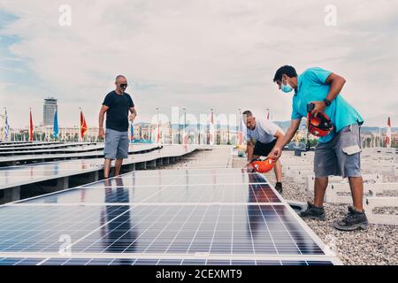 Group of male engineers installing modern solar batteries in industrial facility of modern plant Stock Photo