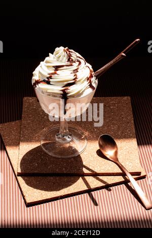 Chocolate ice cream topped with cream and chocolate sauce placed on cork coasters on table Stock Photo