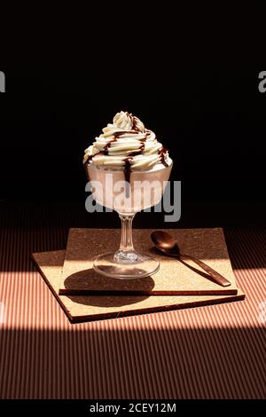 Chocolate ice cream topped with cream and chocolate sauce placed on cork coasters on table Stock Photo