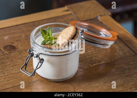 Closeup of palatable cheesecake in glass jar garnished with chocolate chip cookie and sprig of mint Stock Photo