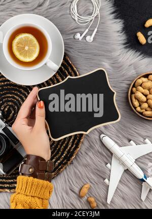 Womans hand in sweater with old instant camera plane and tea Stock Photo