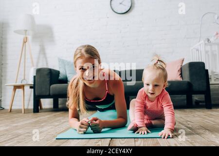 Sportswoman doing plank near child on fitness mat Stock Photo