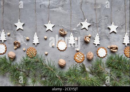 Winter Christmas arrangement with various cookies and nuts placed with green spruce branches and handmade decorations on gray background Stock Photo