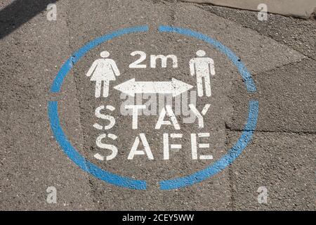 Pavement marker in a UK town centre warning people to keep 2 meters apart during the 2020 coronavirus covid-19 pandemic Stock Photo