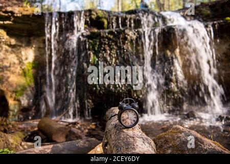 Retro alarm clock on waterfall background. Abstract photo of time. Stock Photo