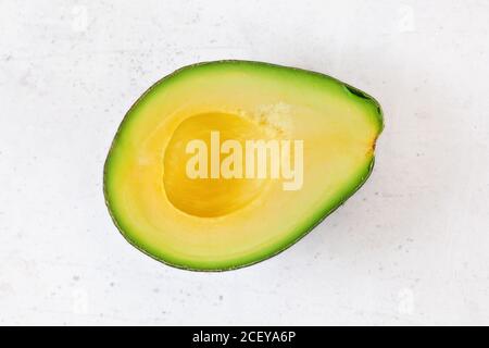 Top down view, halved avocado with yellow fruit pulp on white stone board Stock Photo