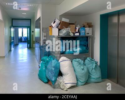 in the corner of a hospital corridor different garbage bags are piled up Stock Photo