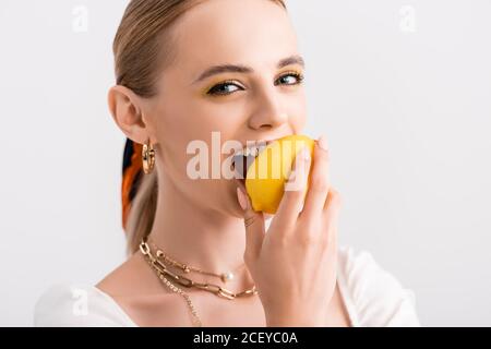 rustic blonde woman biting yellow lemon isolated on white Stock Photo