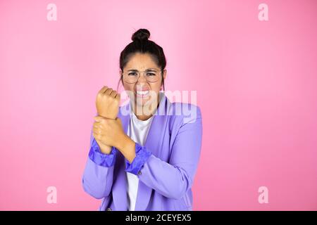 Young beautiful business woman over isolated pink background suffering pain on hands and fingers, arthritis inflammation Stock Photo