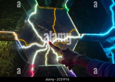 Electricity, education, science, futuristic and physics concept. Woman touching plasma panel display. Interactive touchscreen exposition in science Stock Photo