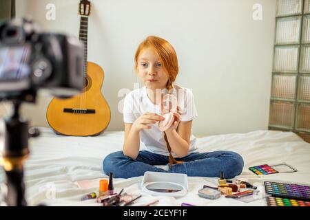 little caucasian girl want to be beauty blogger, she records video on professional camera. girl enjoy being interesting for subscribers. indoors Stock Photo