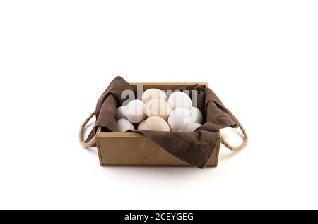 Chicken eggs are white and brown in a beautiful wooden package with a brown linen napkin. Stock Photo