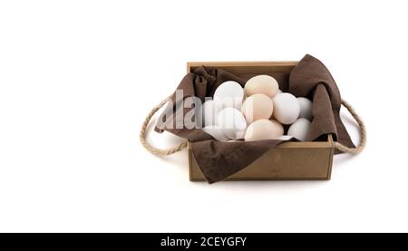 Chicken eggs are white and brown in a beautiful wooden package with a brown linen napkin. Stock Photo